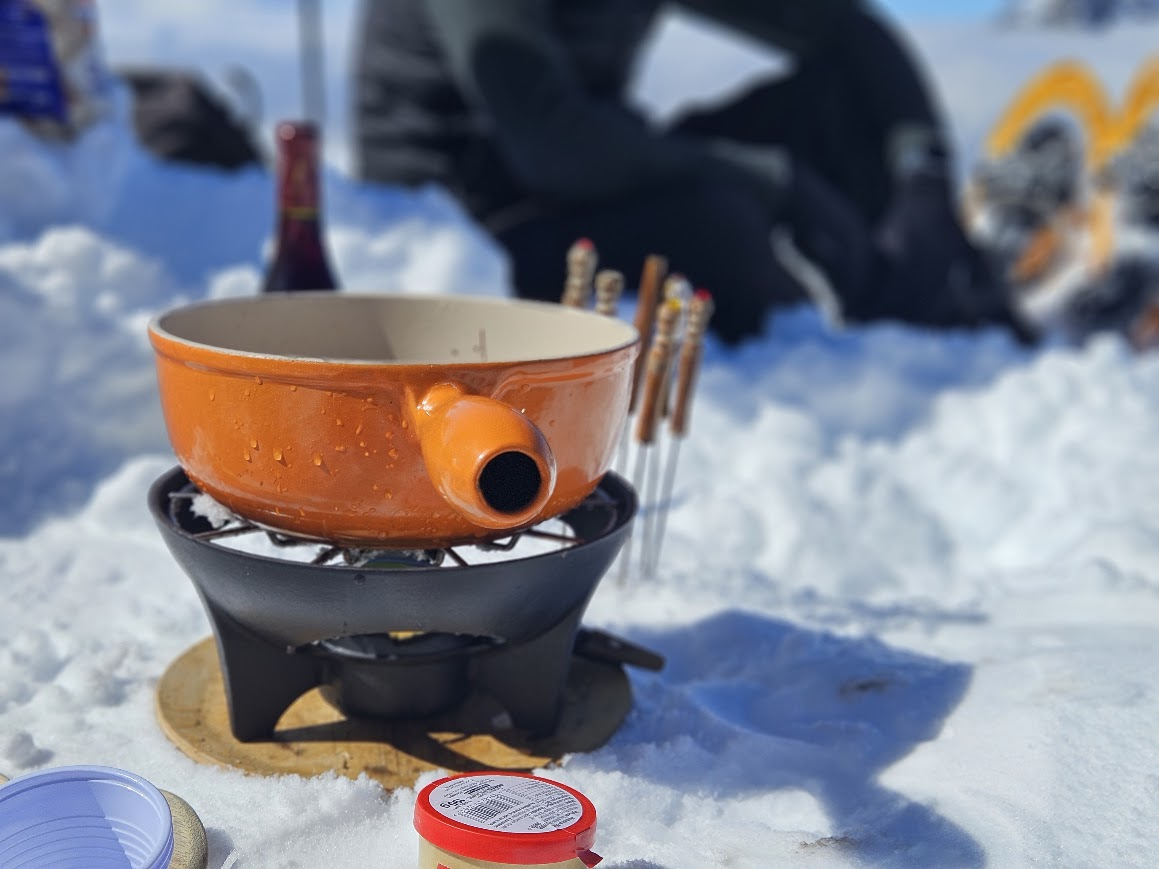 Caquelon de fondue savoyarde posé sur la neige, au Grand-Bornand